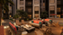 Charming outdoor lounge featuring cozy seating around a modern fire pit, with lush greenery and ambient lighting enhancing the evening atmosphere.