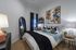 Cozy modern bedroom featuring a plush bed with decorative pillows, stylish artwork, and a chic full-length mirror.