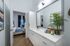 Sophisticated bathroom with a sleek vanity and large mirror, leading into an inviting bedroom with stylish decor and natural light.