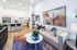 Chic open-plan living room and kitchen with modern decor, cozy beige sofa, and vibrant artwork, perfect for stylish living.