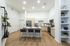 Modern kitchen with sleek cabinetry, spacious island seating for three, and elegant lighting; complemented by natural wood flooring and stylish decor elements.