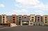 Modern apartment building with vibrant facades and welcoming leasing center under a clear blue sky.