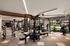 Modern, well-equipped gym with diverse fitness machines and expansive windows overlooking a lush garden.