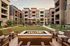 Chic courtyard with a cozy fire pit area, surrounded by modern apartment buildings and lush greenery, perfect for relaxation.