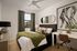 Elegant bedroom with a chic design featuring a large bed with plush pillows, modern decor, and a stylish desk area under natural light.