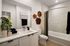 Elegant bathroom featuring modern white cabinetry, sleek countertops, and unique wooden wall decor, creating a serene ambiance.