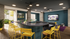 Modern entertainment area featuring a sleek curved bar with vibrant yellow stools, stylish lounge seating, and a large TV, perfect for social gatherings.