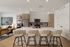 Chic modern kitchen with sleek cabinetry, large island, and elegant seating, opening to a cozy living space.
