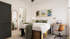 Modern bedroom featuring a cozy bed with green accents, stylish wall art, and a functional workspace with a laptop, perfect for urban living.