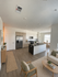 Bright, open-concept kitchen and living space with chic modern decor, featuring hardwood floors, sleek cabinetry, and a cozy seating area.