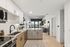 Sleek modern kitchen with granite countertops, open concept leading to a bright living area with stylish decor and a large window view.