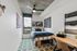 Modern urban bedroom with stylish decorations, featuring cozy bed, vibrant artwork, and ample sunlight through a large window.