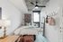 Cozy contemporary bedroom featuring a plush bed, stylish decor, wall art, and large window with a city view.