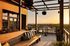 Modern rooftop patio with elegant wooden seating, stylish tables, and panoramic sunset views.