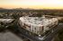 Aerial view of a modern urban apartment complex surrounded by lush greenery and scenic mountain views at sunset.