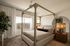 Elegant bedroom featuring a modern canopy bed, large window with natural light, and stylish decor creating a serene ambiance.