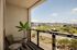 Modern balcony with cozy seating and panoramic views of urban landscape and mountains.