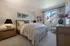 Serene bedroom with a cozy ambiance, featuring a plush bed, elegant bedside lamps, and large window with garden view.