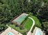Lush apartment complex view featuring a tennis court nestled amid vibrant greenery and a crystal-clear swimming pool, offering a serene outdoor experience.