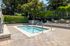 Inviting and serene outdoor hot tub surrounded by lush greenery and a stylish stone patio, perfect for relaxing in nature.