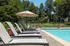 Inviting outdoor pool area with modern lounge chairs, umbrellas, and lush greenery, perfect for relaxing and soaking up the sun.