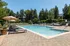 Luxurious outdoor pool area with elegant lounge chairs, surrounded by lush green trees and modern landscaping for a serene retreat.