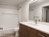 Modern bathroom with sleek wooden cabinetry, elegant fixtures, and a spacious vanity mirror, highlighting contemporary design.