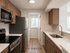 Modern kitchen with stainless steel appliances, elegant wood cabinetry, and sleek countertops in a bright apartment setting.