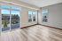 Pet-Friendly Apartments in Brooklyn Park, MN - Urbana Court Apartments - Bright Empty Living Room With Large Windows, Sliding Glass Door To A Balcony, And Wood Look Flooring.