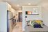 Pet-Friendly Apartments in Minneapolis, MN - B-Side - Cozy Studio Kitchen With Bed, Stainless Steel Appliances, White Oak Flooring, Recessed Lighting, and Entry Hallway View.