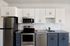 Dog-Friendly Apartments in Minneapolis, MN - B-Side - A Two-Bedroom Kitchen With White Cabinets, Blue-Base Cabinets, Quartz Countertops, and Stainless Steel Appliances.