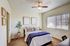 Apartments in North Las Vegas, NV, With In-Unit Washer and Dryer - Desert Ridge Apartments - Bedroom With Bed, Plush Carpet, Ceiling Fan, Wall Frames, and Window With Vertical Blinds.