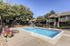 Aurora, CO, Apartments Near Southlands Mall - Canterra at Fitzsimons - Outdoor Swimming Pool With Sundeck, Lounge Chairs, Mature Trees, Metal Fence, and Surrounding Apartment Buildings.