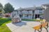 Apartments in Aurora, CO, With In-Unit Washer and Dryer - Canterra at Fitzsimons - Barbeque Area With Grilling Station, Picnic Benches, Green Lawn, and Two-Story Buildings With Balconies.