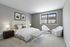 2-Bedroom Apartments in Alsip, IL - Midpointe Apartments - A Bedroom With Upholstered Bed, White Bedding, Nightstands With Lamps, And Large Window.