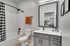 Minneapolis, MN, Pet-Friendly Apartments - B-Side - A Studio Bathroom With Bathtub, Shower Curtain, Single-Sink Vanity, Gray Cabinets, White Countertop, Large Framed Mirror, and Matte Black Fixtures.