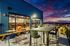 Apartments in Minneapolis, MN, With In-Unit Washer and Dryer - B-Side - Rooftop Lounge With Community Tables, Bar Seating, Outdoor Chairs, and Glass Doors To Resident Lounge With City Views at Dusk.