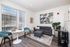 Pet-Friendly Apartments in West Oakland, CA - Prescott Station - Bedroom Features A Neatly Made Bed With White Bedding, A Brown Throw Blanket, A Side Table, Framed Photos, And Wood-Style Floors.
