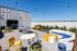 West Oakland, CA, Apartments with In-Unit Washer and Dryer - Prescott Station - Rooftop Features Colorful Outdoor Seating, Round Tables, String Lights Overhead, And A Ping Pong Table.