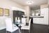 North Austin, TX, Pet-Friendly Apartments - Lotus Village Apartments - A Kitchen With White Cabinets, Black Appliances, Glass Table, And Modern Pendant Lighting.
