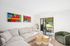 One-Bedroom Apartments in Palatine, IL - The Clayson - A Living Room With A Large Sectional Sofa, Colorful Wall Art, Woven Ottomans, And Sliding Glass Door To Patio.