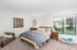 1-Bedroom Apartments in Palatine, IL - The Clayson - A Bedroom With Carpeted Flooring, Nightstands, 2-Seater Couch, Wall Art, And A Large Window.
