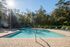 Inviting outdoor swimming pool surrounded by lounge chairs under vibrant sunshine at a serene location.