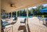 Luxurious outdoor lounge with poolside seating under ceiling fans, surrounded by lush greenery.