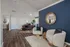 Chic community clubhouse with modern furniture, navy accent wall, and wooden floor.