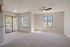 Spacious living room with carpet flooring, sliding glass doors to a balcony, and a ceiling fan.
