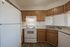 Inviting kitchen with wooden cabinets, white appliances, and sleek countertops.