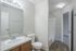 Bright and modern bathroom with wooden cabinetry, white countertop, and a spacious shower area.