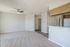 Elegant living room with plush carpet, modern ceiling fan, and open access to kitchen area.