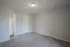 Bright bedroom with plush carpet and neutral walls leading to a clean bathroom.